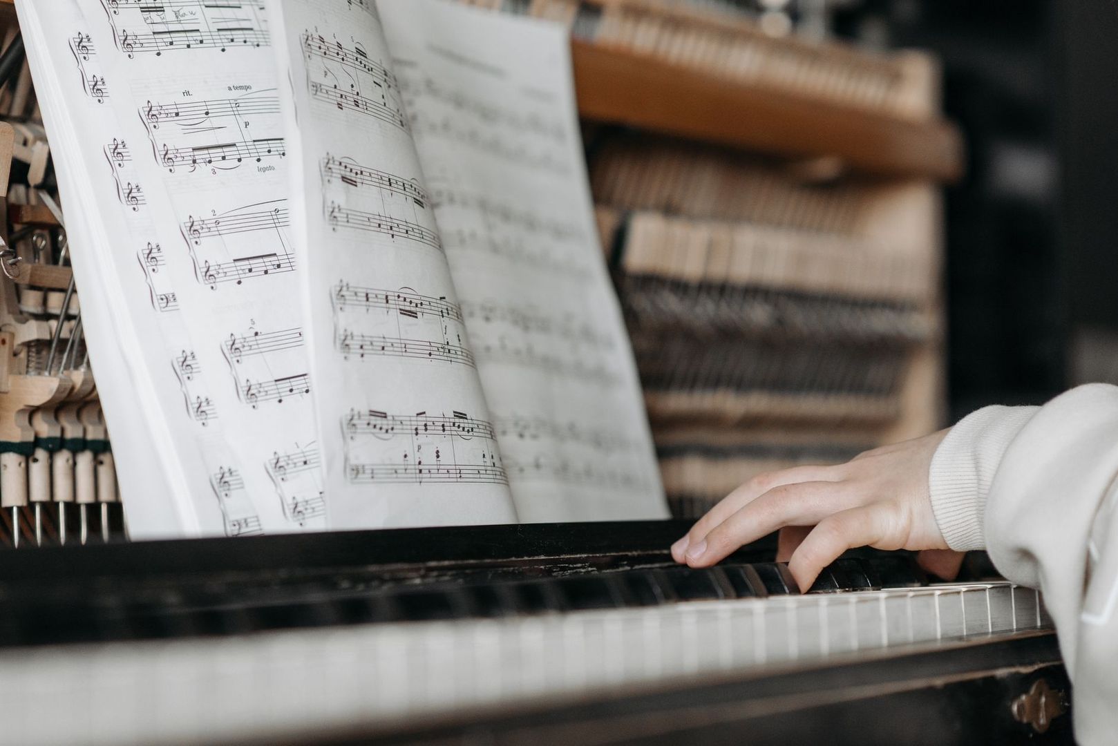 Open bladmuziek boven een piano met spelende handen