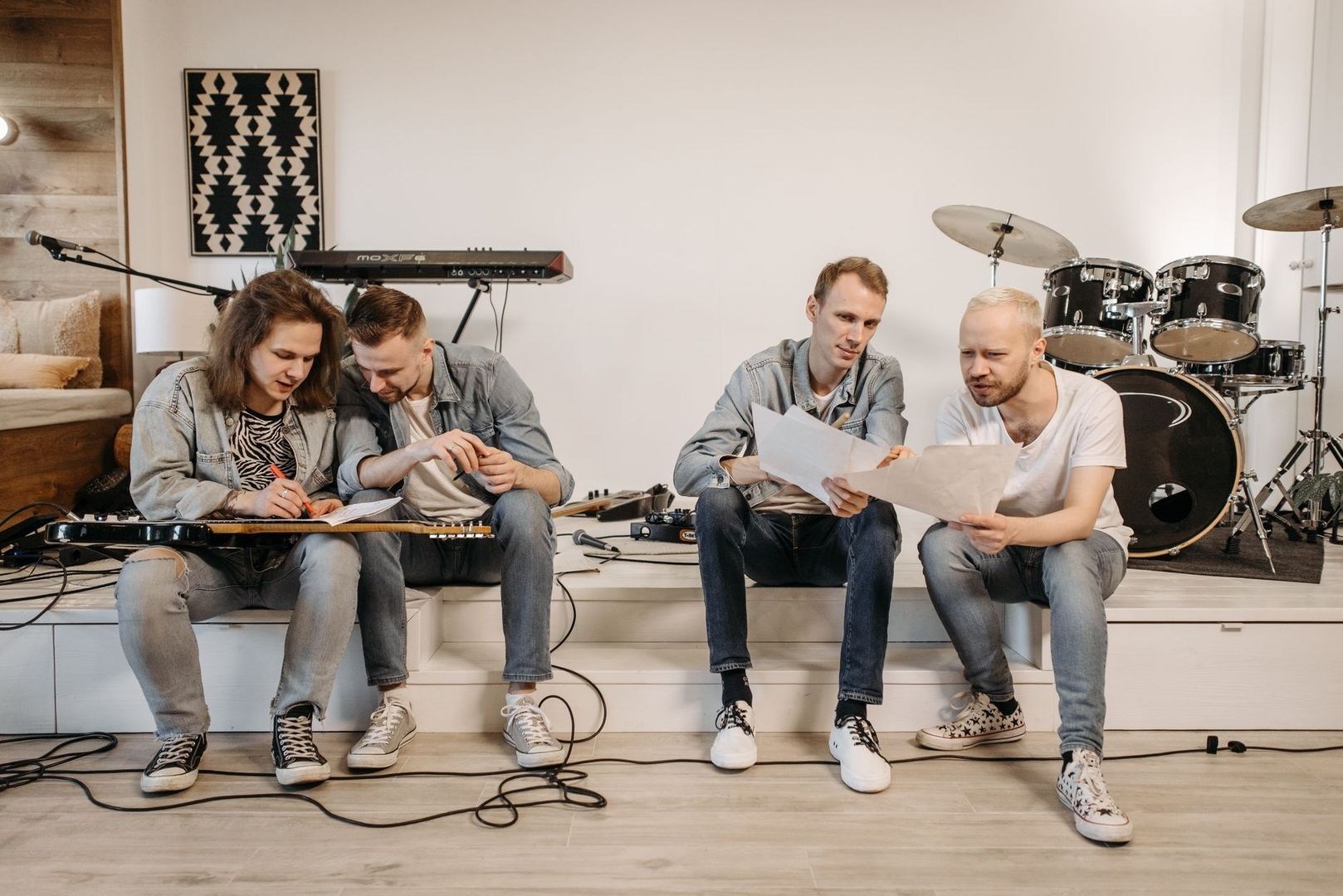 Vier muzikanten bespreken bladmuziek tijdens een repetitie
